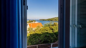 A view from a window overlooking a body of water, greenery, and a distant bridge. - Mljet Gem in Pomena!! (Pomena)