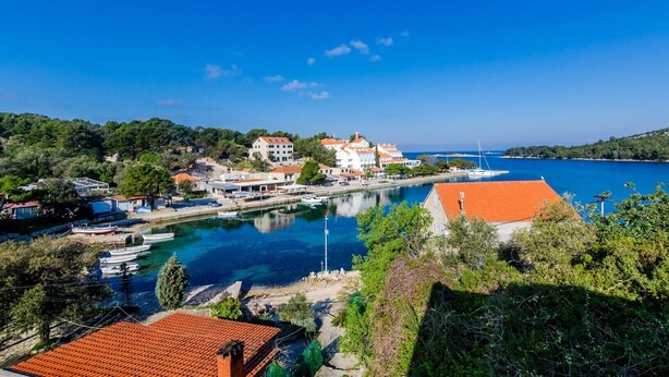 A coastal town with buildings along the waterfront, boats docked, and a clear blue sky. - Mljet Gem in Pomena!! (Pomena)