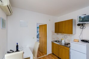A compact kitchen with wooden cabinets, a built-in microwave, and a small refrigerator. - Mljet Gem in Pomena!! (Pomena)