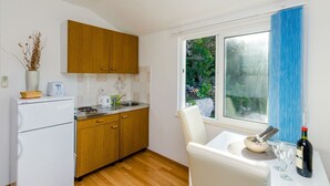 Una cocina compacta con armarios de madera, un refrigerador blanco, un lavamanos y una zona de comedor con mesa y sillas.