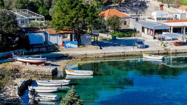A coastal town with boats docked near the shore, a small building with a sign, and a clear blue waterfront. - Mljet Pearl in Pomena,National Park Mljet (Mljet)