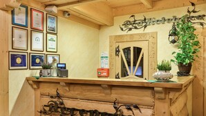 A wooden reception desk with framed awards, a digital display, and a sign reading "Poczta Kotelna". - Pensjonat pod Kotelnica (Bukowina Tatrzanska)