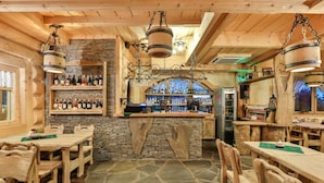 A rustic wooden interior with stone walls, wooden tables and chairs, a bar area with bottles, and a stone floor. - Pensjonat pod Kotelnica (Bukowina Tatrzanska)