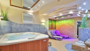 A modern spa area with a hot tub, lounge chairs, and a colorful mosaic wall. - Pensjonat pod Kotelnica (Bukowina Tatrzanska)