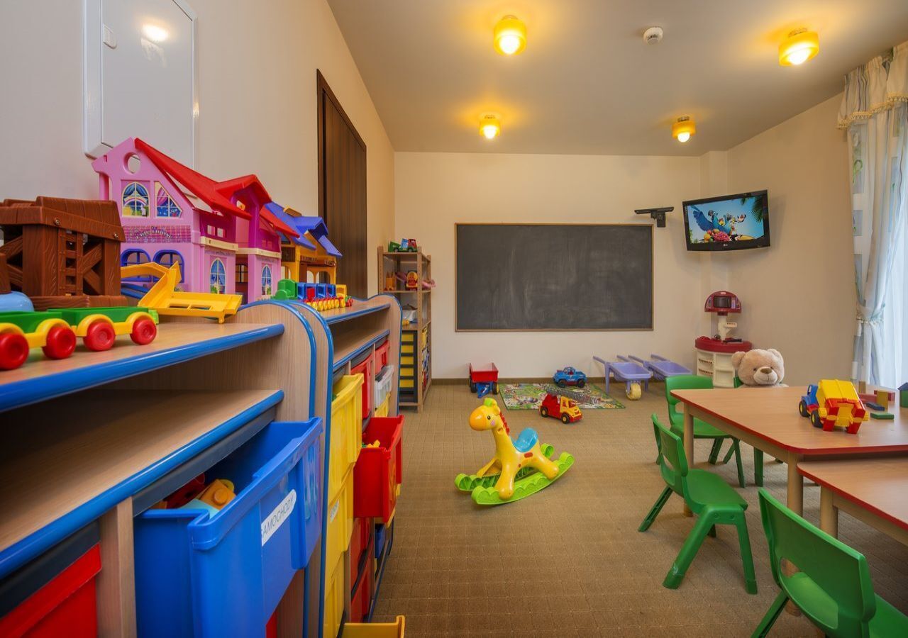 A classroom with colorful toys, a chalkboard, and a television.