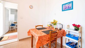 A dining area with a table set for two, a clock on the wall, and a blue-framed painting above the table. - apt Dubrovnik,sea view,near Old tow (Dubrovnik)