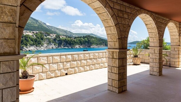 A stone archway overlooking a coastal view with a mountainous backdrop. - White Stone Steel - 2 Bedroom Apartment with Terrace and Sea View (Dubrovnik)