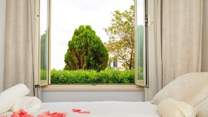 A bedroom with a large window, a bed with white linens, and a view of greenery outside. - White Stone Steel - 2 Bedroom Apartment with Terrace and Sea View (Dubrovnik)