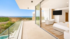 Ein modernes Schlafzimmer mit großem Fenster, einer Badewanne und einem Flachbildfernseher.
