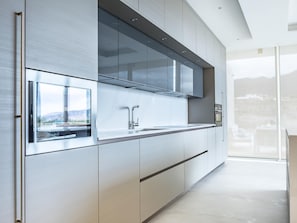 Enjoy cooking with a view from this kitchen, featuring a stainless steel sink, oven, and large window overlooking the outdoors.