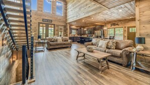 A spacious living area with a staircase, wooden floors, and a large window.