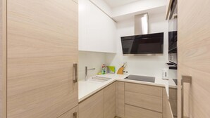 Una cucina compatta con forno a microonde, lavello e pensili.