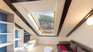 Un dormitorio tipo loft moderno con tragaluces, estanterías empotradas, un sofá y un reposapiés blanco.