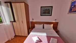 Une chambre d’hôtel avec un lit, une table de chevet, une armoire et un tableau encadré au mur.