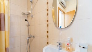 Une salle de bain avec une douche, un lavabo, un miroir et un savon.