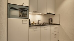 A modern kitchen with white cabinets, a built-in oven, and a dark countertop.