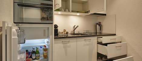 Eine moderne Küche mit weißen Schränken, einem eingebauten Kühlschrank und einem Fliesenboden.