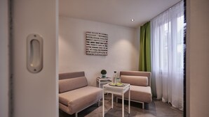 A modern living room with two sofas, a small table, and a wall-mounted artwork.