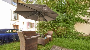 An outdoor seating area with wicker furniture and a large umbrella.