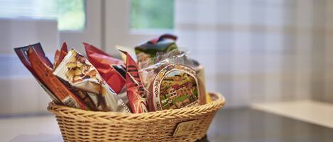 A wicker basket filled with various packaged snacks on a table.