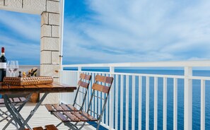 A balcony with a table set for two, a bottle of wine, and two glasses.