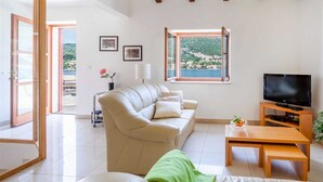 Una sala de estar moderna con un sofá, una televisión y vistas a un paisaje montañoso.