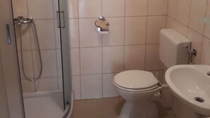 Un baño con ducha de vidrio, inodoro, bidé y lavamanos.