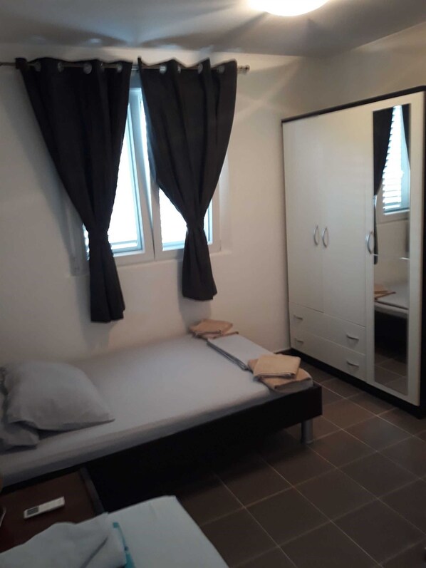 A bedroom with a single bed, a wardrobe, and a window with curtains.