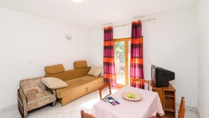 Een knusse woonkamer met een bank, een tafel met appels en een televisie.
