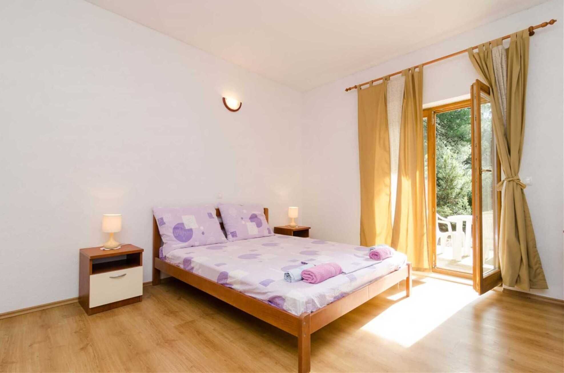 Ein Schlafzimmer mit einem hölzernen Bett, zwei Nachttischen, einer Wandleuchte und einem Fenster mit Vorhängen.