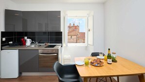 Eine moderne Küche mit dunklen Schränken, einem eingebauten Backofen und einem Essbereich mit Tisch für zwei Personen.
