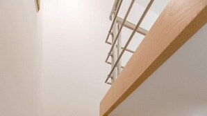 Una escalera de madera con barandilla de vidrio que lleva a un espacio interior blanco.