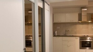 Una cocina moderna con armarios blancos, horno de acero inoxidable y suelo de madera.