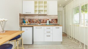 A modern kitchen with white cabinetry, a built-in microwave, and a tiled backsplash. - #SEA SHELL bubble jacuzzi (Dubrovnik)