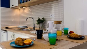 Une cuisine équipée d’un évier, d’une machine à café, d’une bouilloire et d’un panier à fruits.