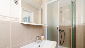 Une salle de bain équipée d’un lavabo, d’un miroir et d’une douche à parois de verre.