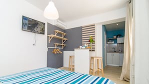 Una habitación moderna con cama, escritorio y kitchenette.