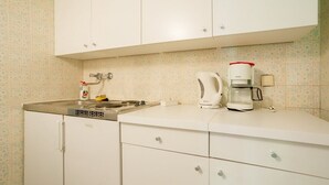 Une cuisine avec des meubles blancs, une machine à café et un lave-vaisselle.
