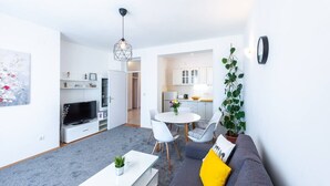 Ein modernes Wohnzimmer mit Sofa, Couchtisch, Fernseher und Essbereich.