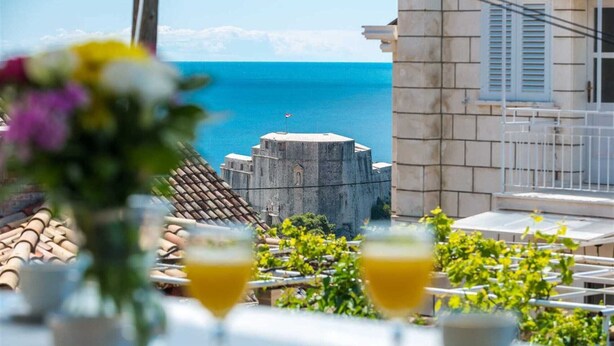 Eine Terrasse mit Meerblick, ein Steinhaus und ein Tisch mit Getränken.