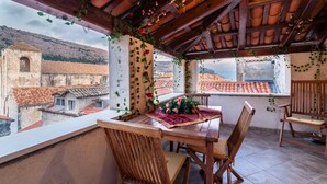 A cozy outdoor dining area with a wooden table and chairs, surrounded by a wooden pergola with climbing plants. - Daniela Old Town three bedroom apartment (Dubrovnik)