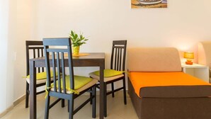 A small, cozy room with a bed, two chairs, a table, and a nightstand with a lamp. - Perfect Studio on Lapad Peninsula 1 (Dubrovnik)