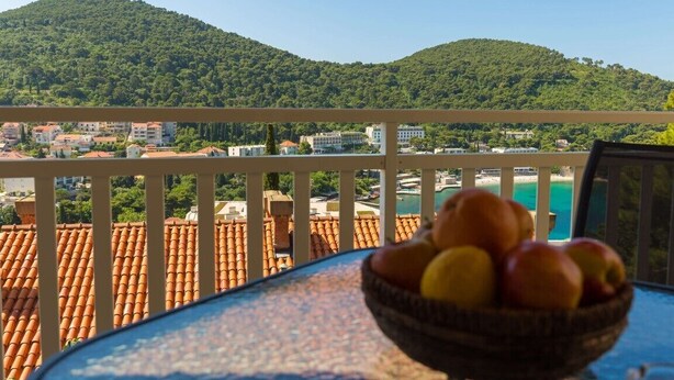 A balcony with a view of a hillside, a bowl of fruit, and terracotta rooftops. - Perfect Studio on Lapad Peninsula 1 (Dubrovnik)