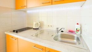 A kitchen with orange cabinets, a stainless steel sink, and a coffee maker. - Perfect Studio on Lapad Peninsula 4 (Dubrovnik)