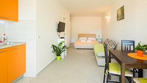 A compact hotel room with a kitchenette, a bed, a dining area, and a TV. - Perfect Studio on Lapad Peninsula 4 (Dubrovnik)