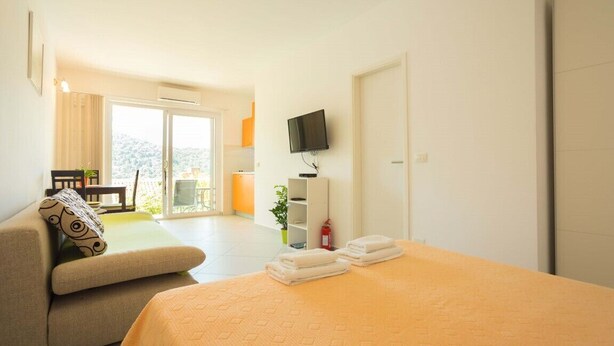 A hotel room with a bed, a sofa, a TV, and a balcony with a view. - Perfect Studio on Lapad Peninsula 4 (Dubrovnik)