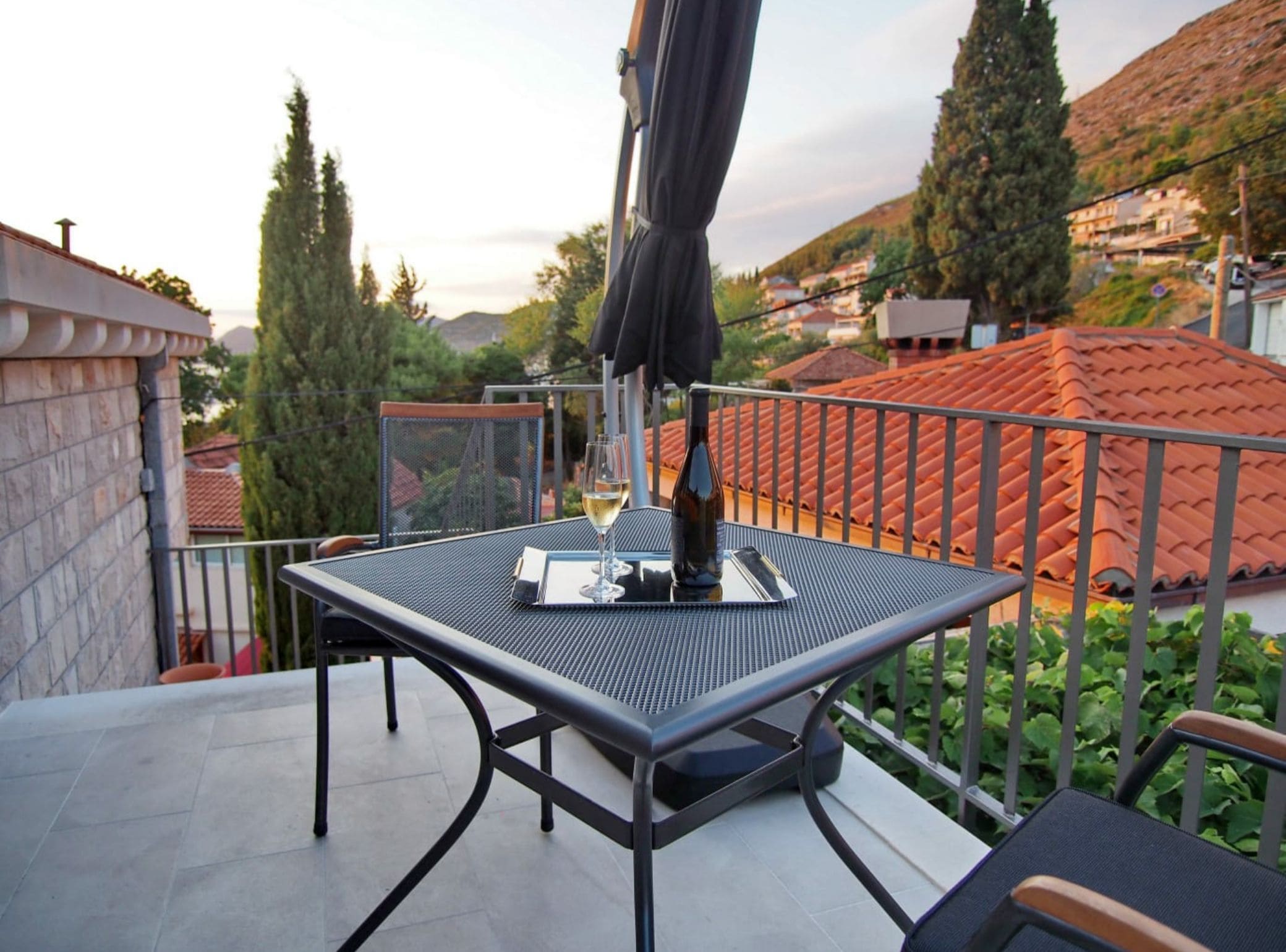 A balcony with a table and chairs, a bottle of wine, and a glass of white wine.