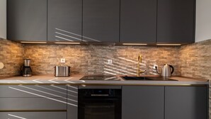 Cocina moderna con armarios oscuros, salpicadero de piedra e iluminación debajo de los gabinetes.