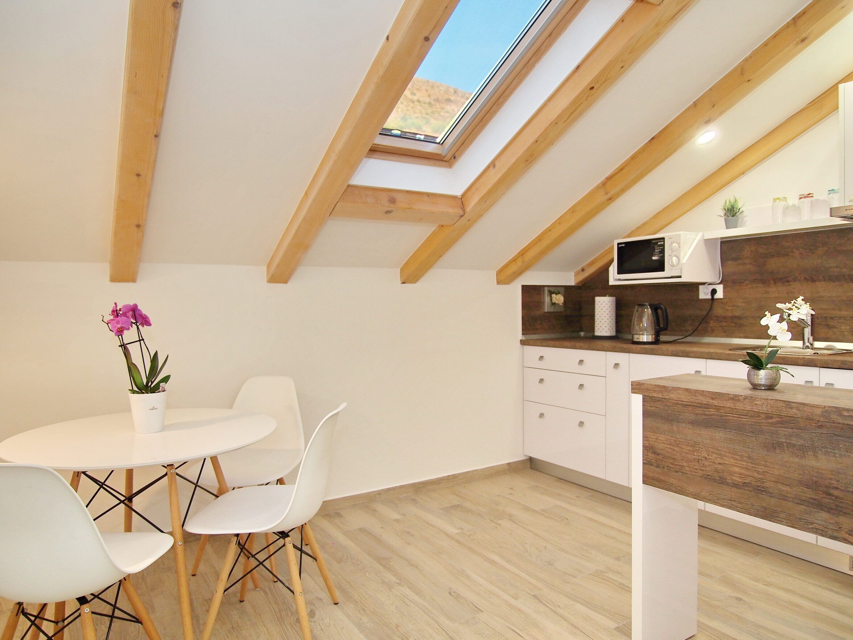 A modern kitchen with a skylight, white cabinets, and a wooden countertop.