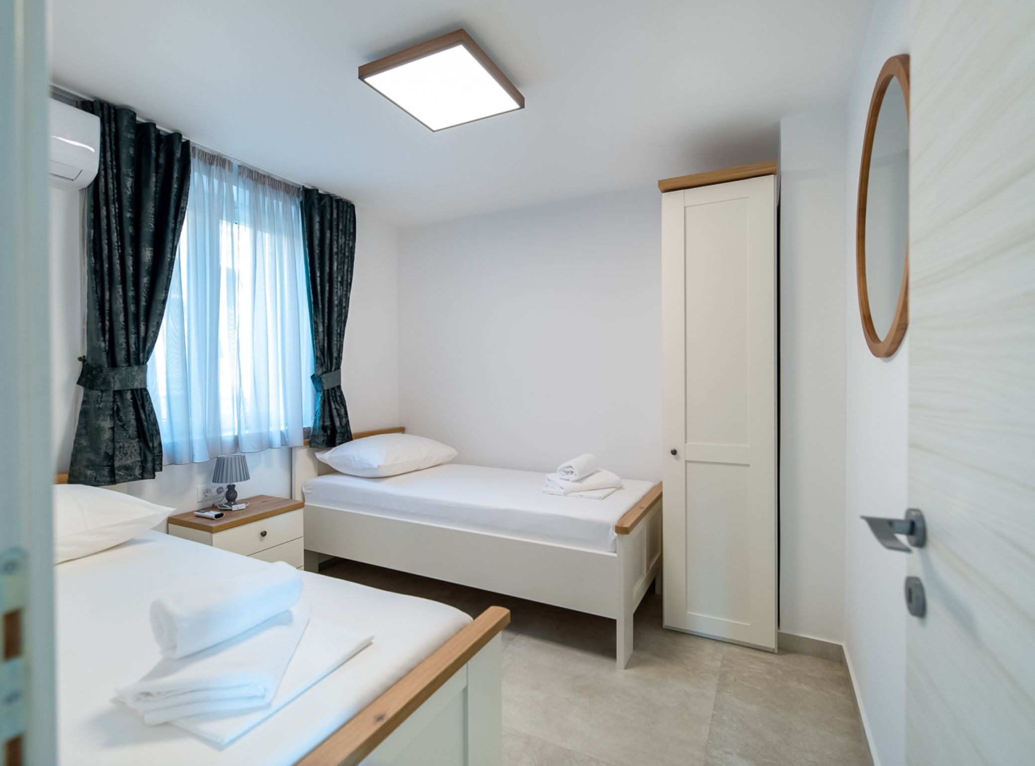 A small, clean room with a single bed, a bedside table, a lamp, and a wardrobe.